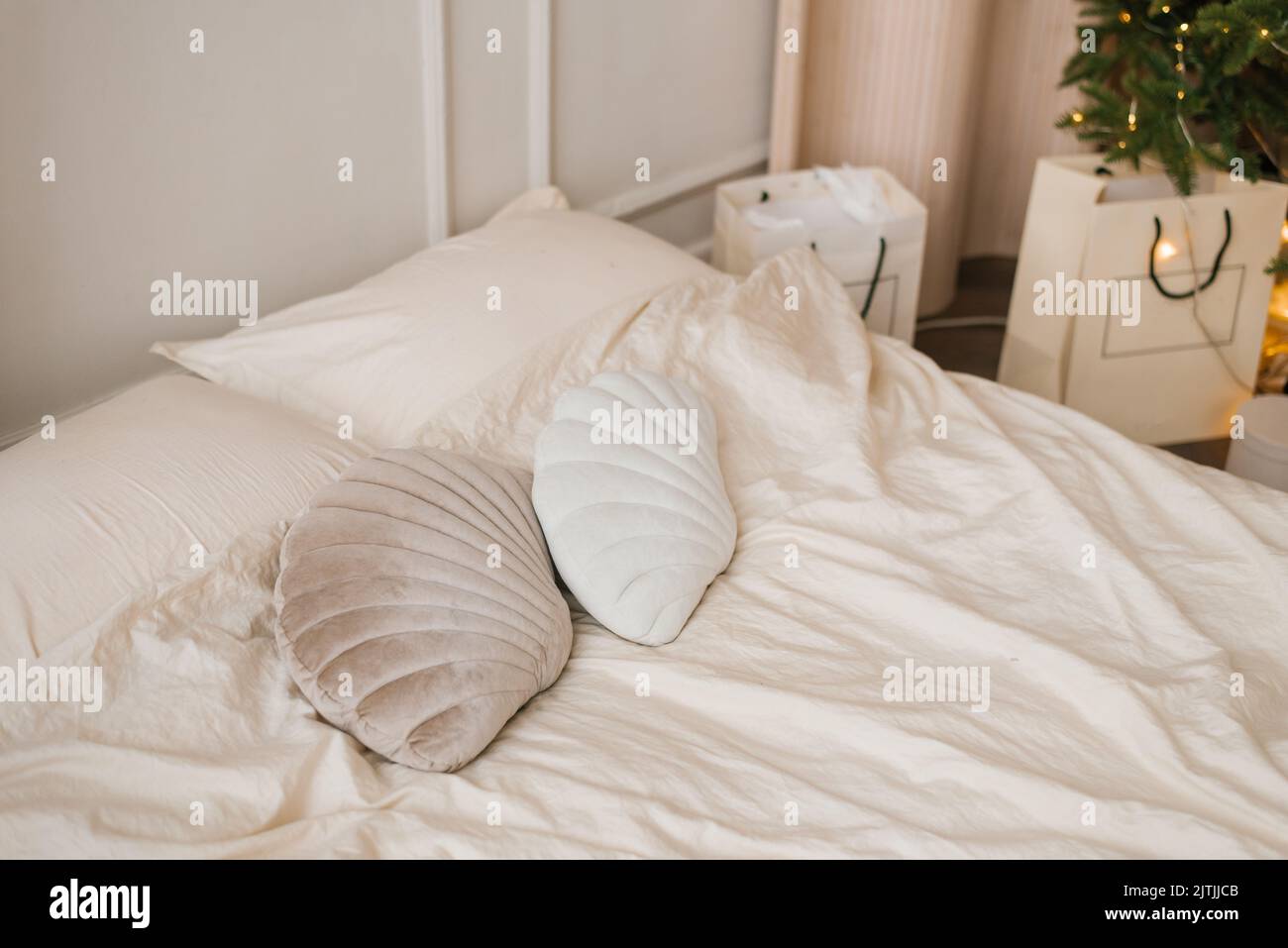 Cuscini a forma di conchiglie giacciono su un letto leggero nella camera da letto, decorata per Natale Foto Stock