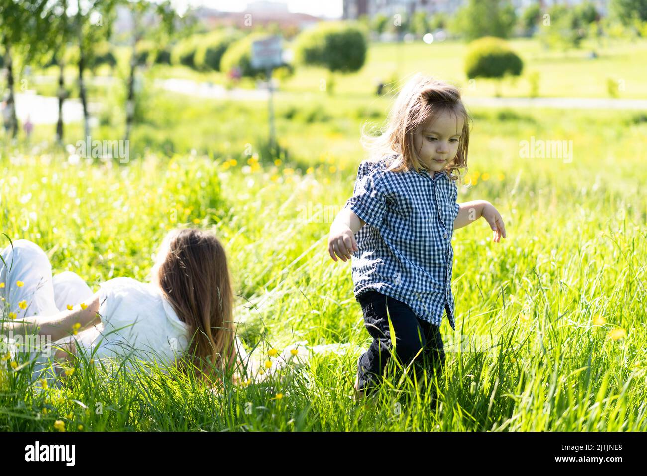 Fratello e sorella corrono felicemente e ridono sull'erba verde . Il sole splende, i bambini ballano incautamente. Il concetto di una vita familiare felice e legame. Stile di vita. Foto Stock