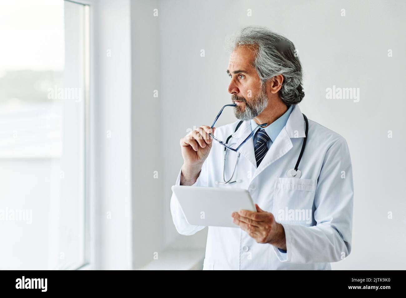 anziani capelli grigi attivi medico ospedale medicina salute clinica ufficio ritratto occhiali uomo stetoscopio specialista tablet computer Foto Stock