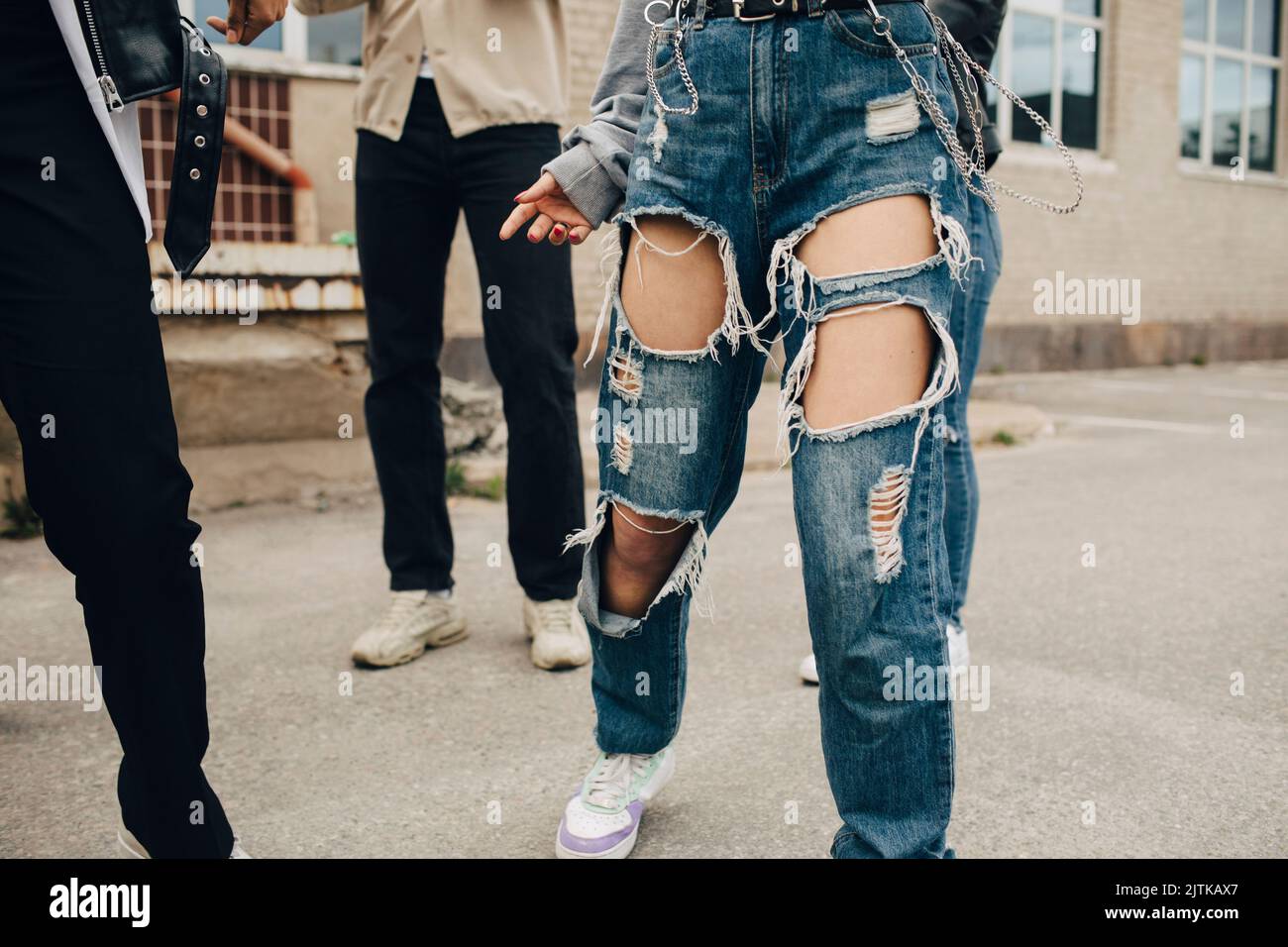 Bassa sezione di donna che indossa jeans strappati ballare con gli amici sulla strada Foto Stock