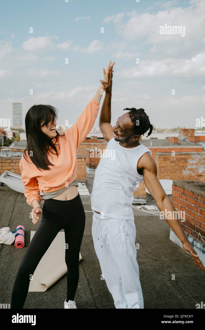 Donna allegra che dà high-five ad amico maschio sul tetto Foto Stock