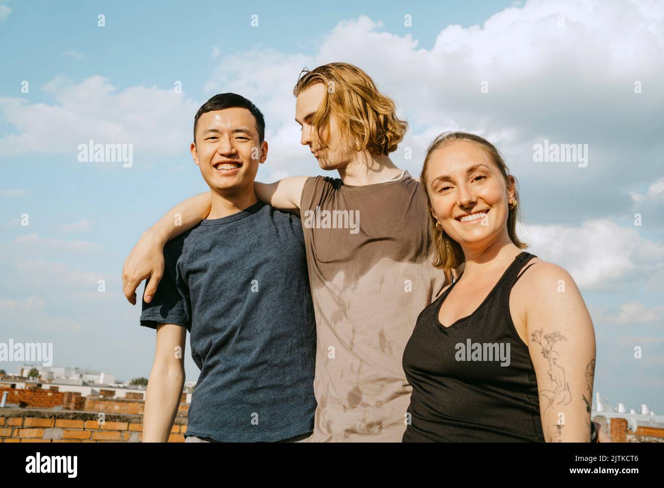 Ritratto di amici multirazziali felici in piedi contro il cielo nella giornata di sole Foto Stock