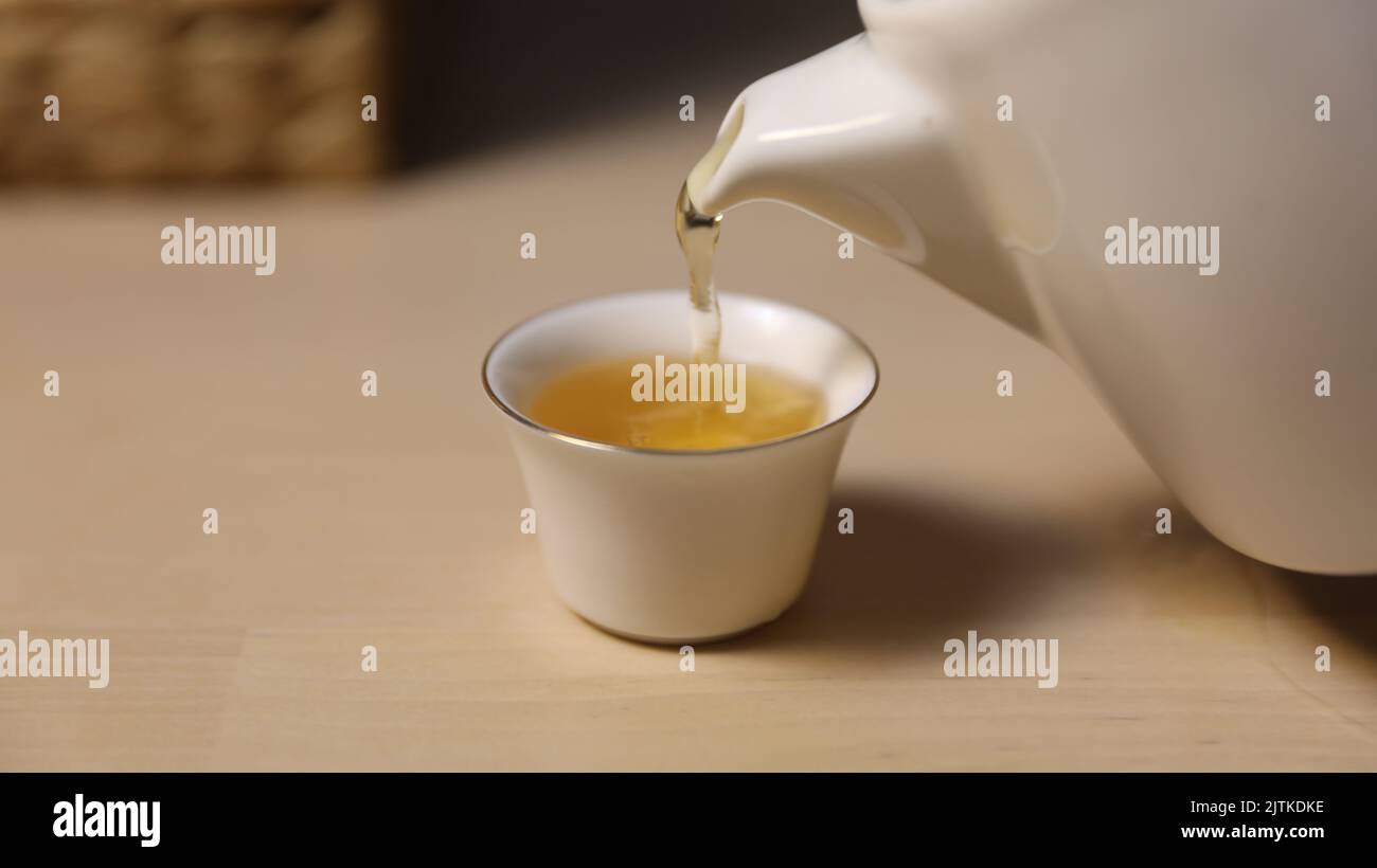 Versare il tè in una tazza da tè Foto Stock