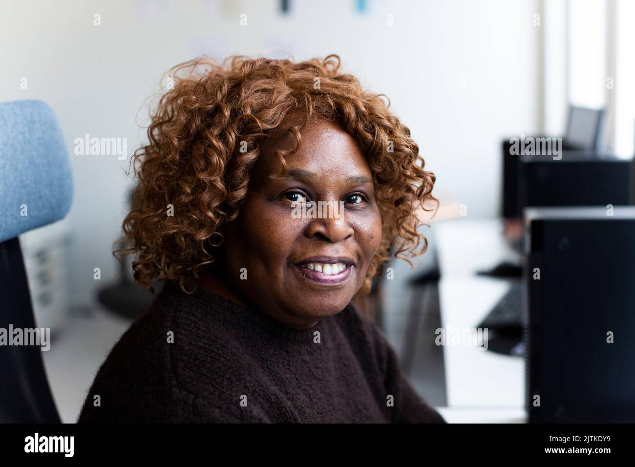 Imprenditrice sorridente seduto in ufficio Foto Stock