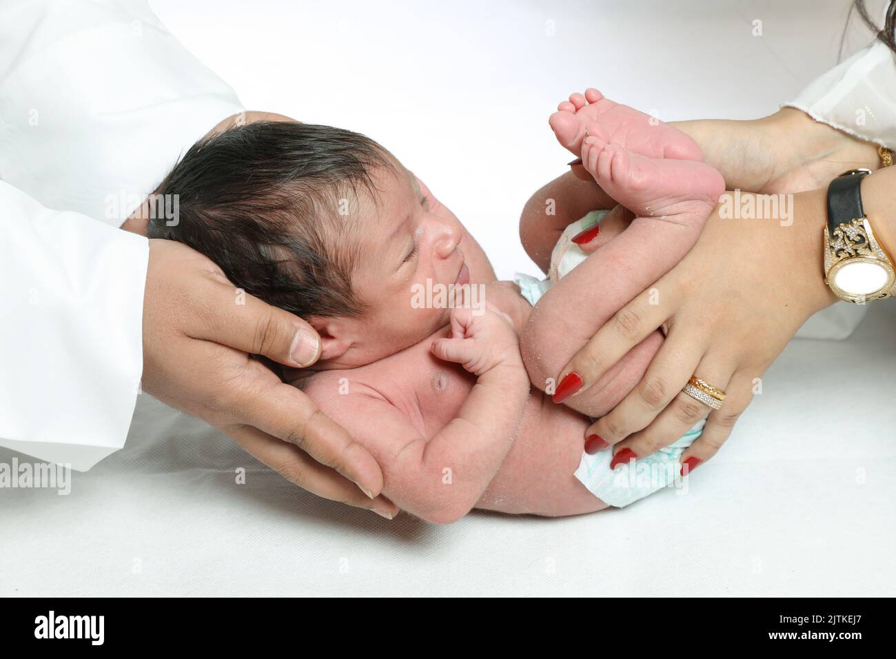 Bambino piccolo ragazzo in mani premurose closeup genitori tenendo neonato famiglia Arabia Saudita esprimendo concetto di fiducia Foto Stock