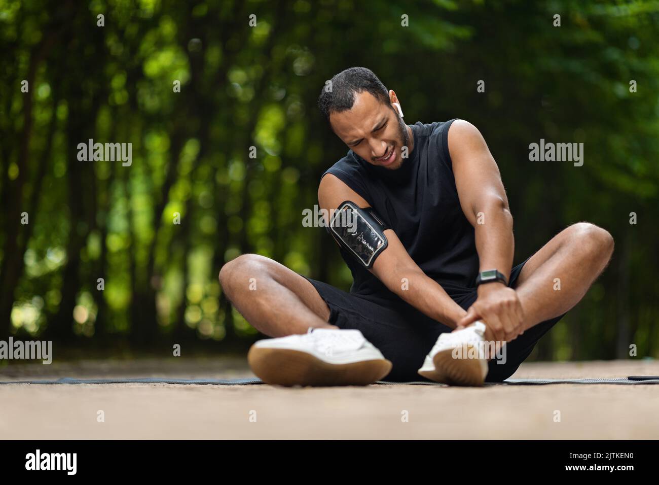 Sportivo afro-americano nel dolore che tocca la caviglia, copia spazio Foto Stock