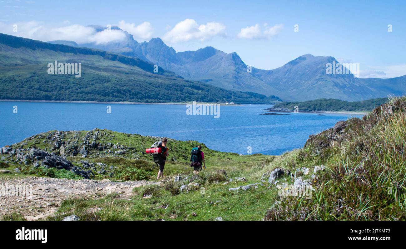 Isola di Skye, Regno Unito. 18 luglio 2022. Gli escursionisti camminano vicino a loch Slapin nell'isola scozzese di Skye in una giornata di sole con montagne sullo sfondo. Foto Stock