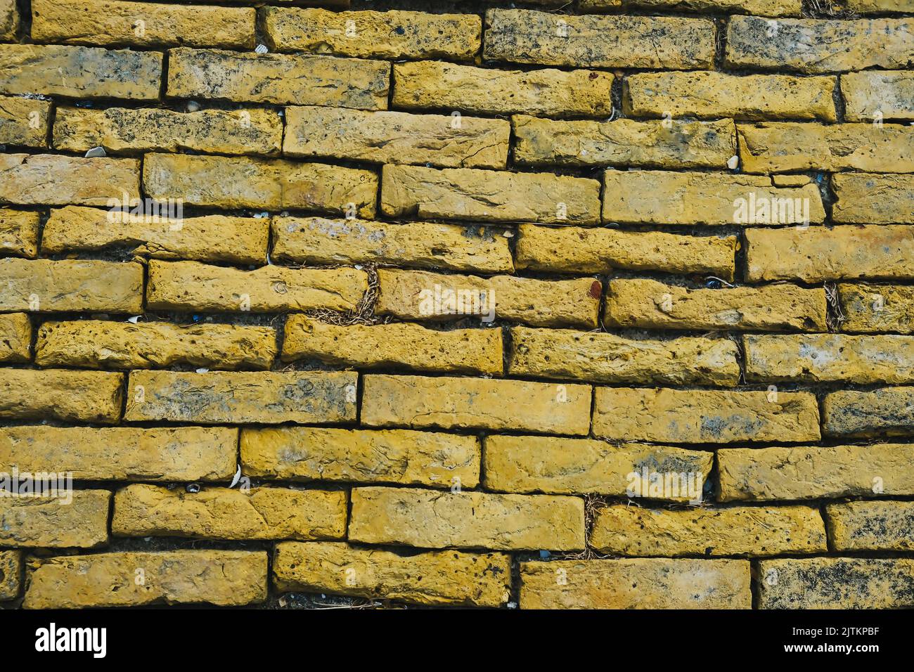 Sfondo del vecchio muro di mattoni gialli intemperiato. Foto Stock