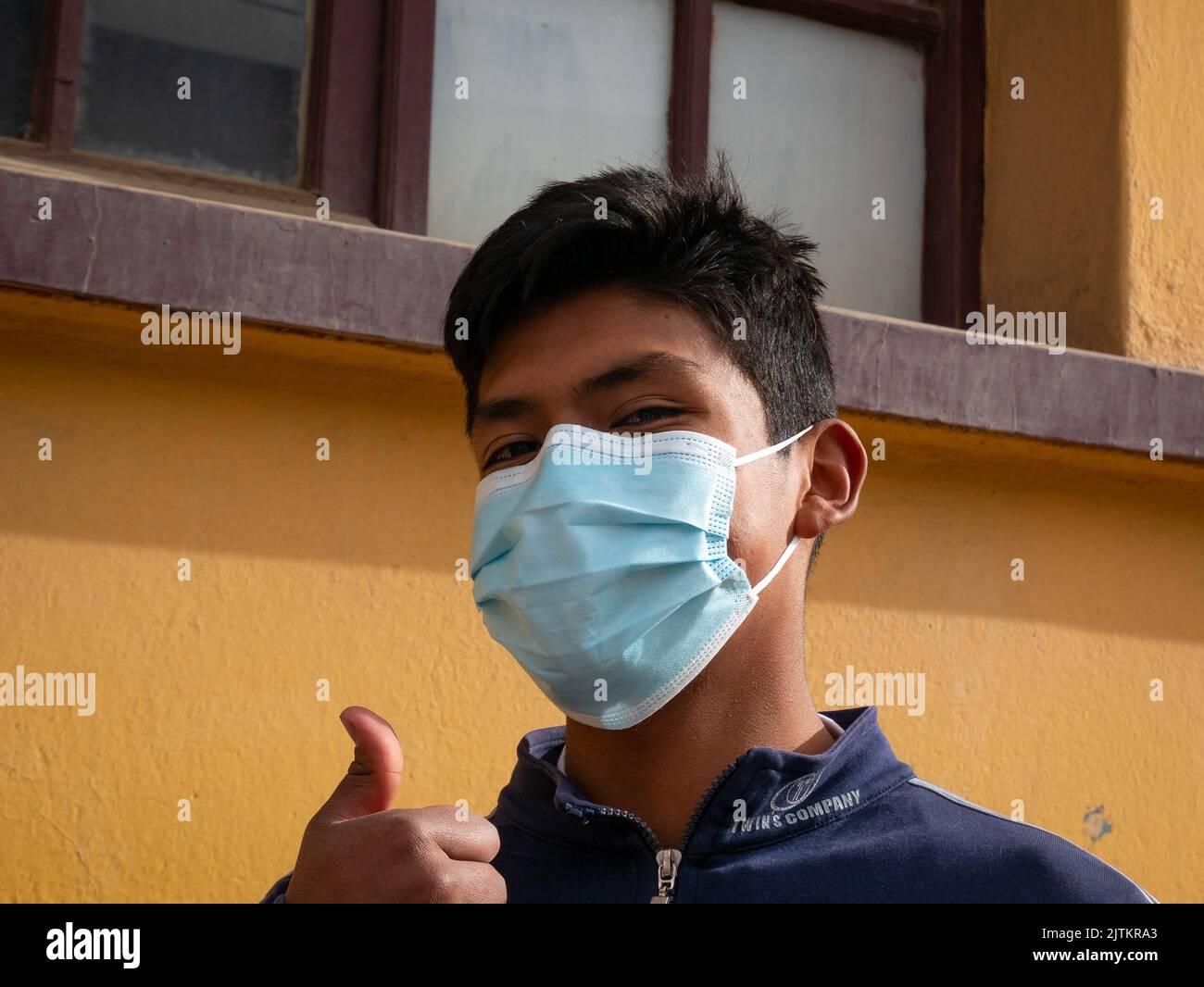 Viacha, la Paz, Bolivia - Agosto 16 2022: Un ragazzo boliviano che indossa una maschera guarda la fotocamera fuori della casa Foto Stock