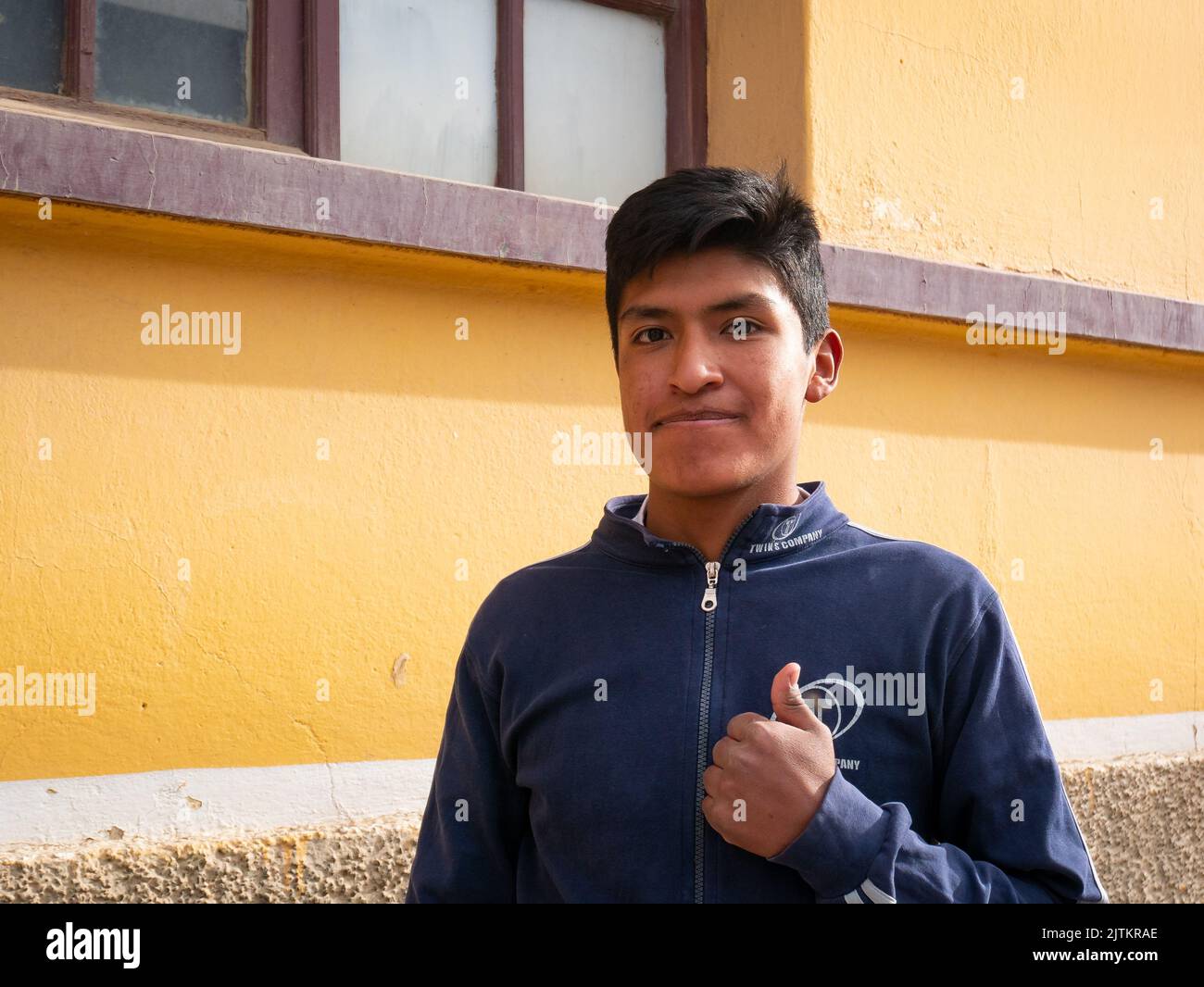 Viacha, la Paz, Bolivia - Agosto 16 2022: Un ragazzo boliviano sorride e guarda la fotocamera fuori della Casa gialla Foto Stock