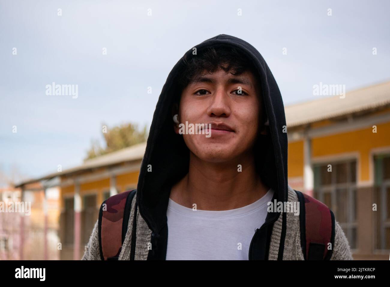 Viacha, la Paz, Bolivia - Agosto 16 2022: Un uomo boliviano che indossa una felpa con cappuccio guarda la telecamera contro il cielo limpido Foto Stock