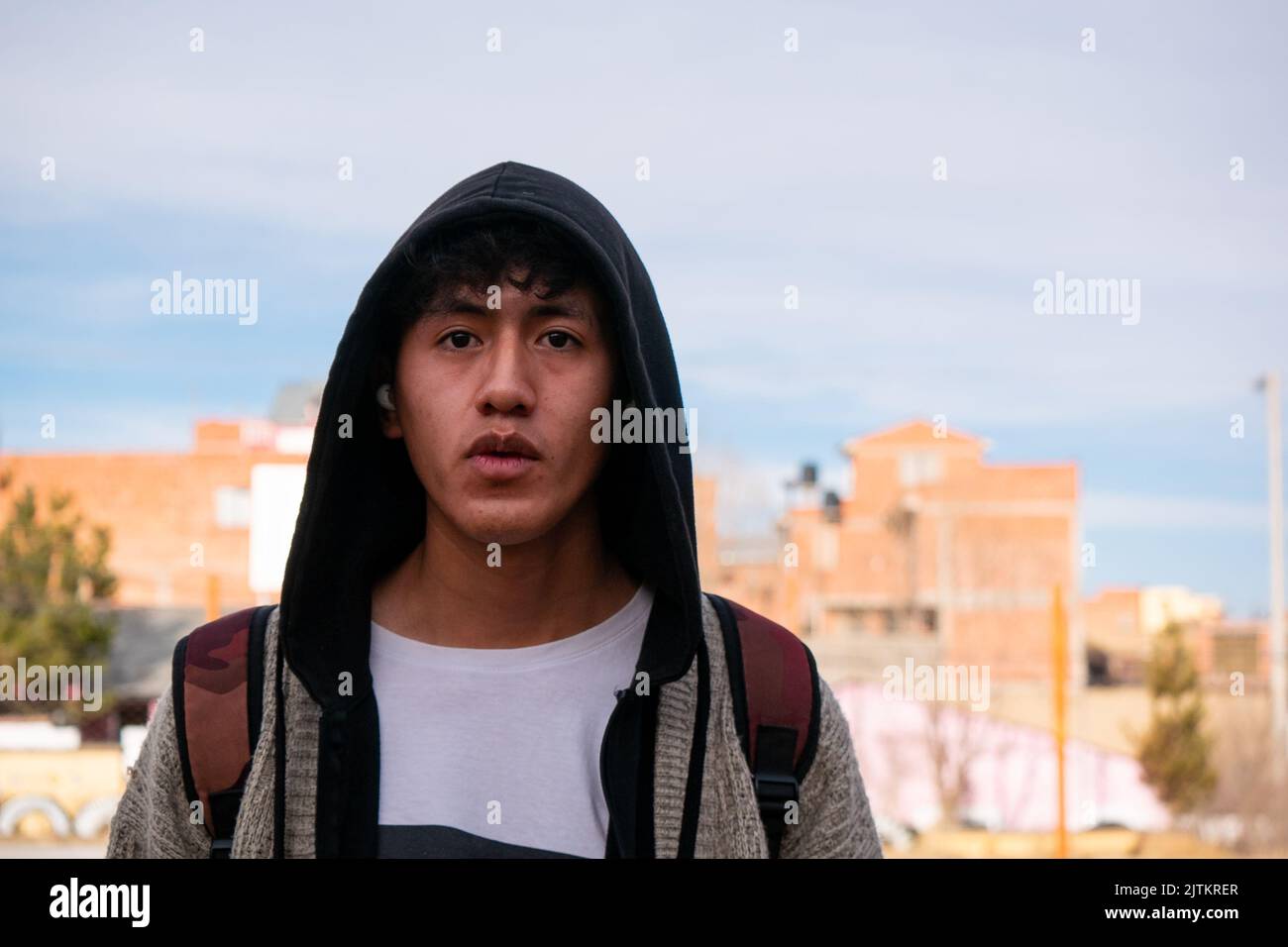 Viacha, la Paz, Bolivia - Agosto 16 2022: Un uomo boliviano che indossa una felpa con cappuccio guarda la telecamera contro il cielo limpido Foto Stock