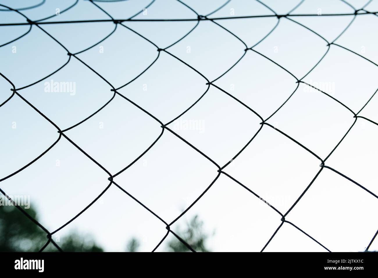 Rete di ferro recinzione contro il cielo blu sfocato. Struttura a forma di diamante. Foto Stock