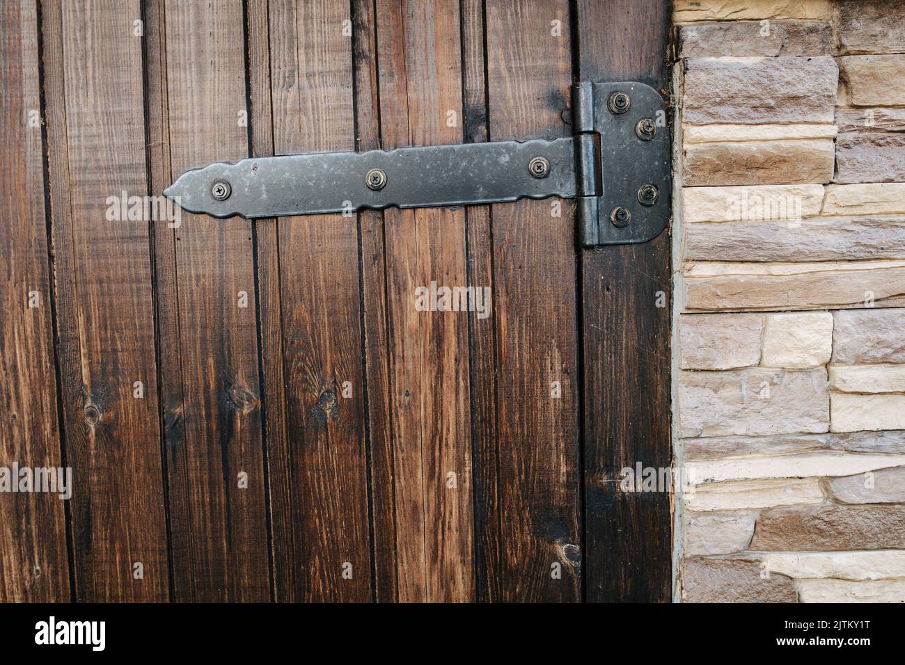 Struttura della porta in legno verniciato. Con cerniere a barra pesanti. Con la copertura artificiale di mattoni di pietra sul muro sul lato di esso. Foto Stock