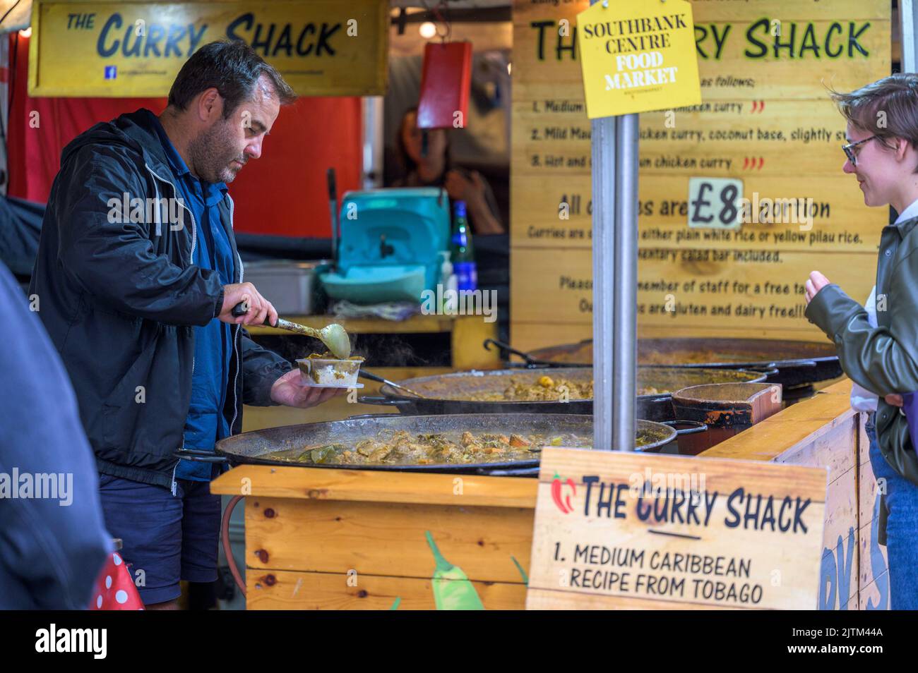 LONDRA - 20 maggio 2022: L'uomo serve curry cliente alla bancarella pop up Street food sulla South Bank Foto Stock