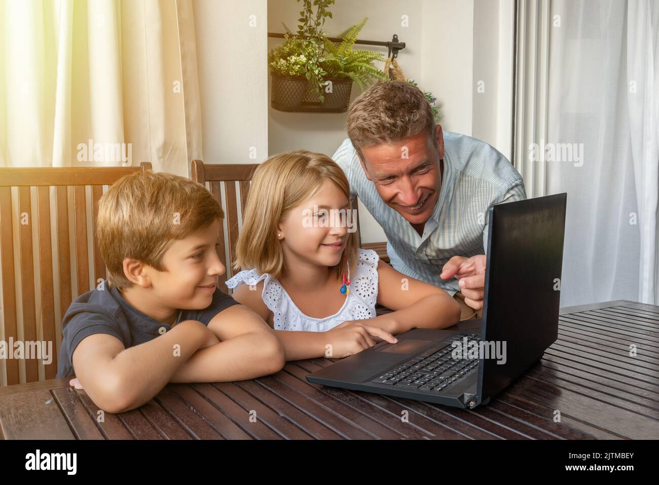 Padre insegna ai suoi figli come usare il notebook. Nuove tecnologie per i compiti scolastici e le attività quotidiane Foto Stock