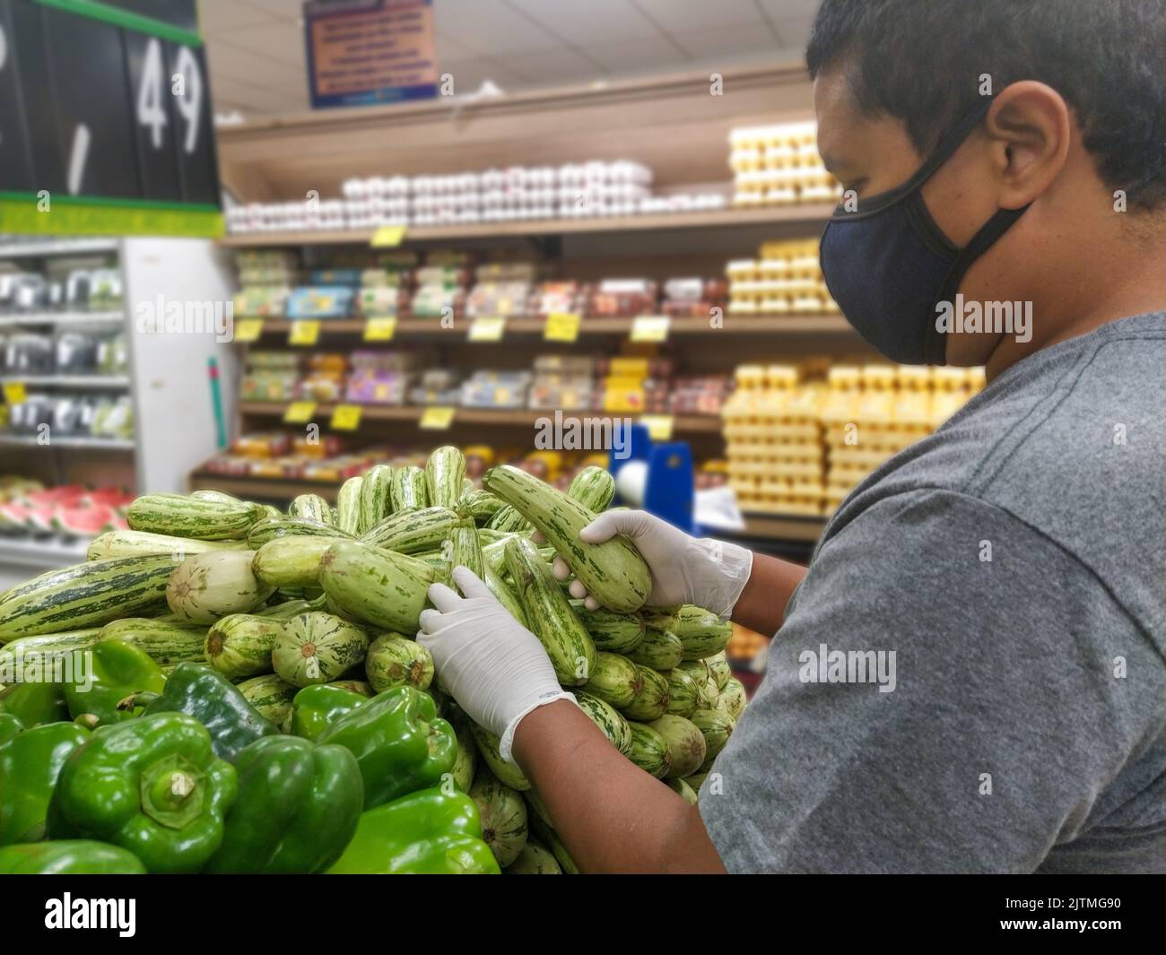 Uomo nero scelta zucchine con guanto, protezione contro il coronavirus in Brasile Foto Stock