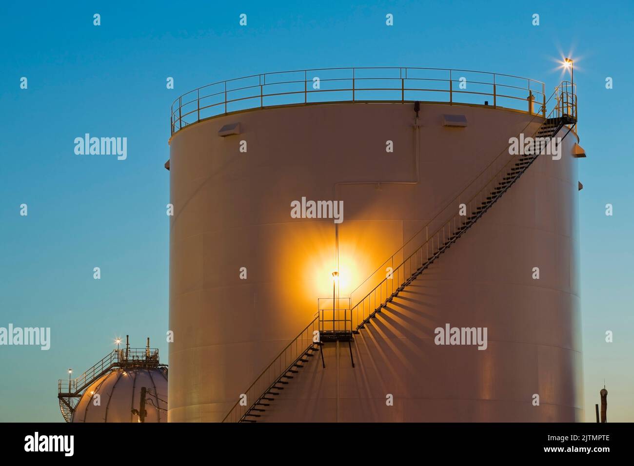 Serbatoi di stoccaggio con scale alla raffineria di petrolio e gas al crepuscolo. Foto Stock
