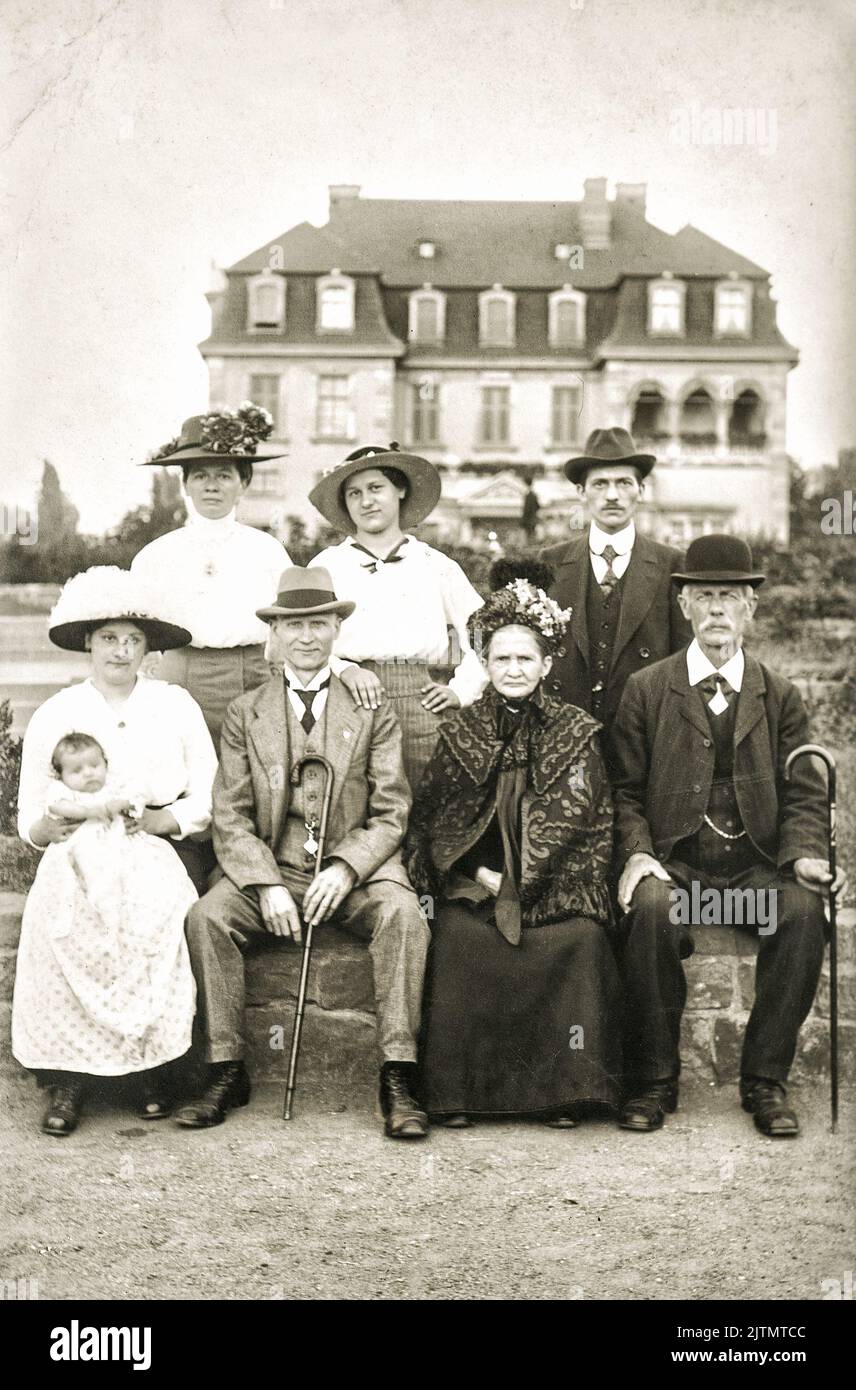Vecchia foto di famiglia con casa. Immagine antica con grana originale del film Foto Stock