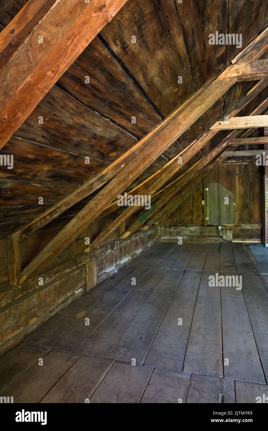 Pavimento in legno, travi e pannelli del tetto nella mansarda vuota di una vecchia casa stile cottage 1800s. Foto Stock