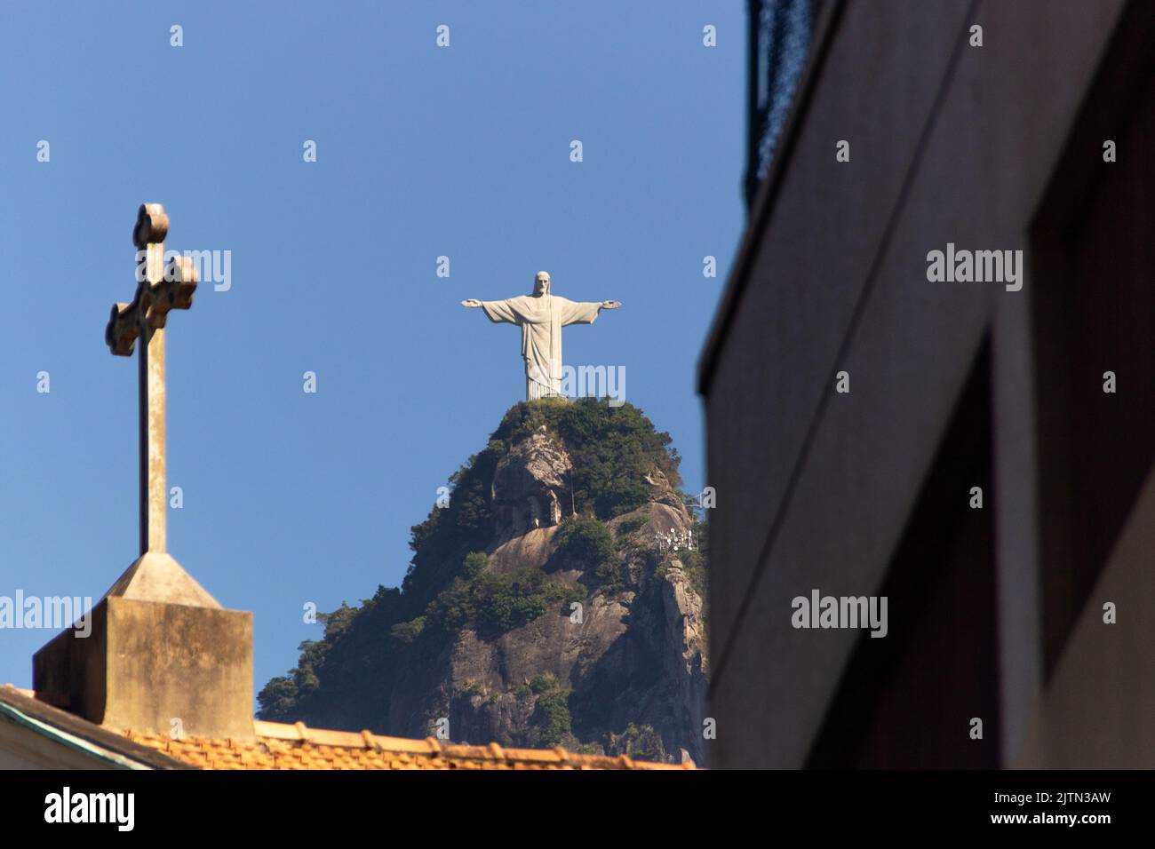 Cristo Redentore e croce di una chiesa, a Rio de Janeiro, Brasile - 12 maggio 2020: Cristo Redentore e croce di una chiesa in primo piano Foto Stock