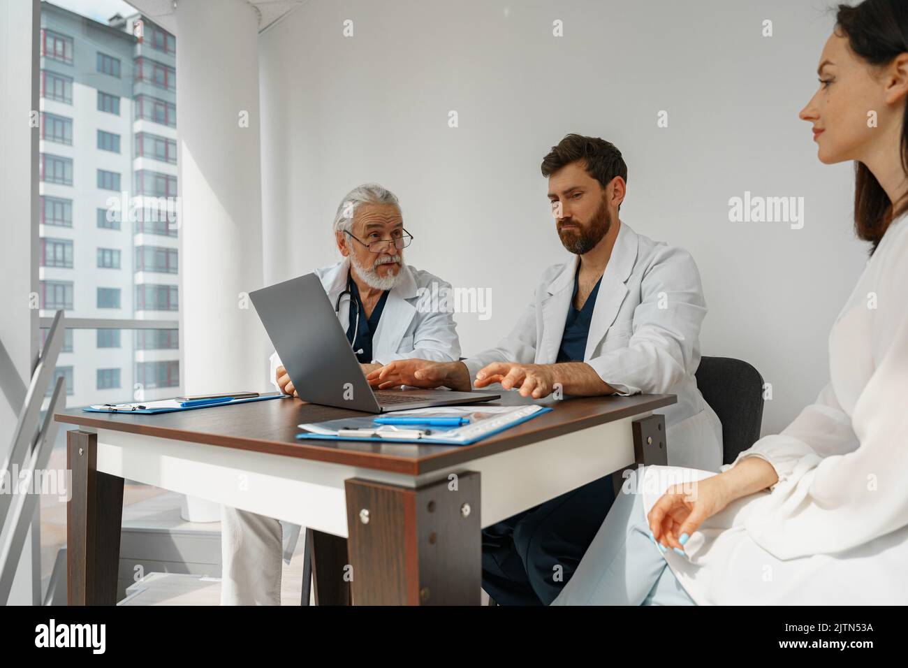 Due medici in uniforme bianca consultano la paziente femminile durante un incontro in clinica medica privata Foto Stock