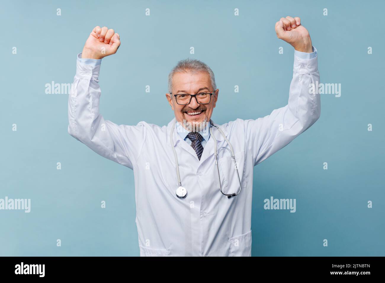 Medico maschio alzando le braccia in vittoria. Concetto di medicina e lotta contro la malattia. Foto Stock