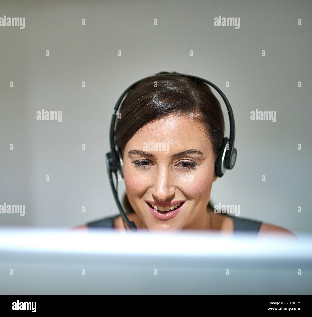 Consente di creare un legame tra cliente e azienda. Una donna professionista che utilizza un computer e un auricolare alla sua scrivania. Foto Stock