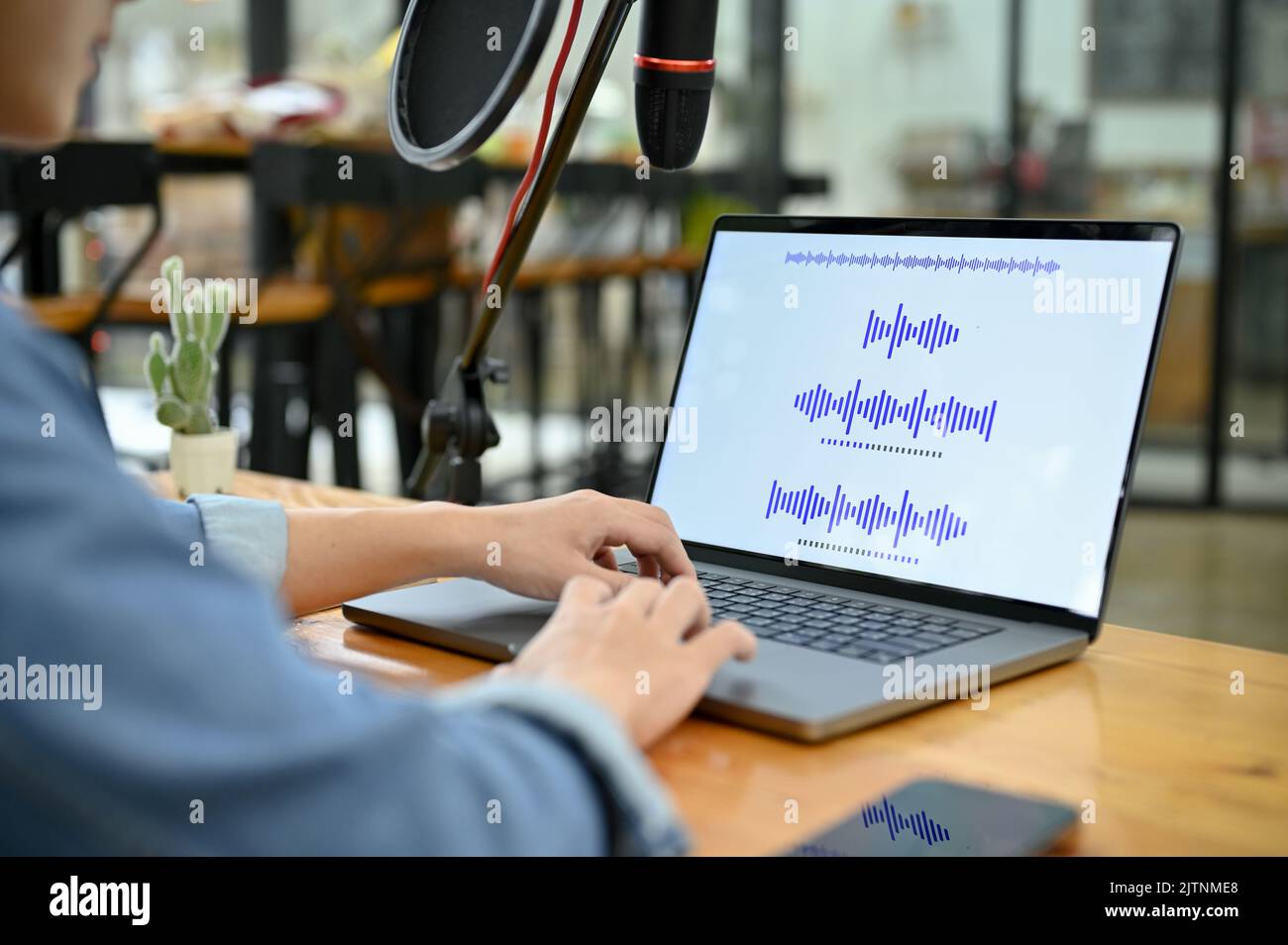 Un professionista asiatico maschio host radio o produttore di radio che regola i suoni di registrazione sul suo computer portatile in studio. Primo piano immagine Foto Stock
