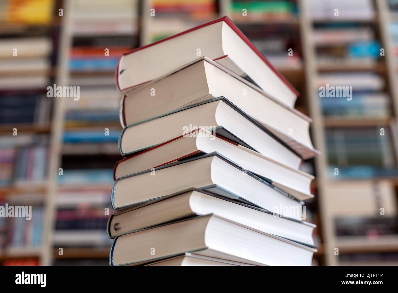 una pila di romanzi davanti a una parete di libri Foto Stock