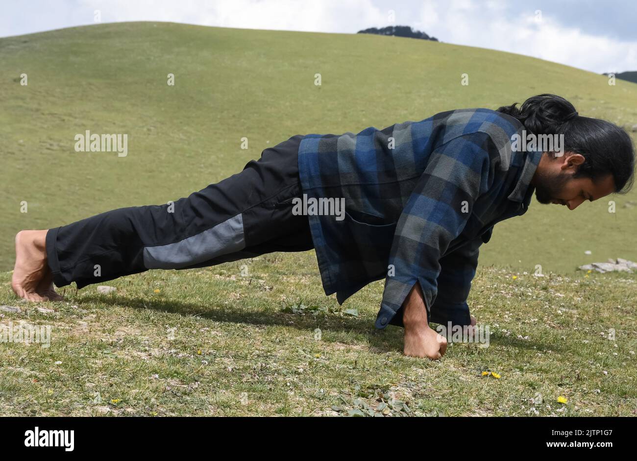 Vista laterale di un giovane indiano dall'aspetto buono che fa il pugno in montagna Foto Stock