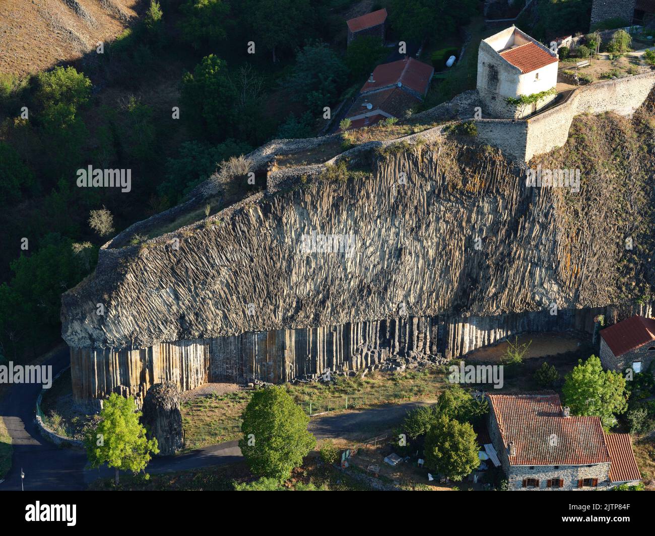 VISTA AEREA. Curiosità geologica di un promontorio vulcanico con colonne di basalto alla sua base. Chilhac, Haute-Loire, Auvergne-Rhône-Alpes, Francia. Foto Stock