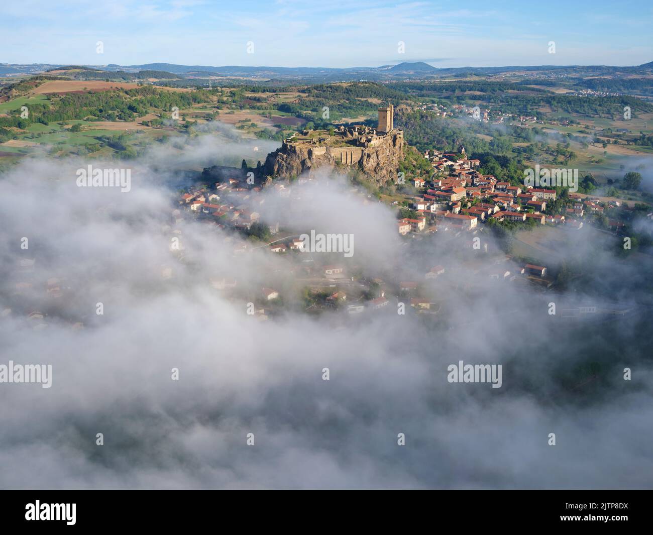 VISTA AEREA. Fortezza di Polignac, su una mesa basaltica con la bassa nebbia mattutina. Polignac, alta Loira, Auvergne-Rhône-Alpes, Francia. Foto Stock
