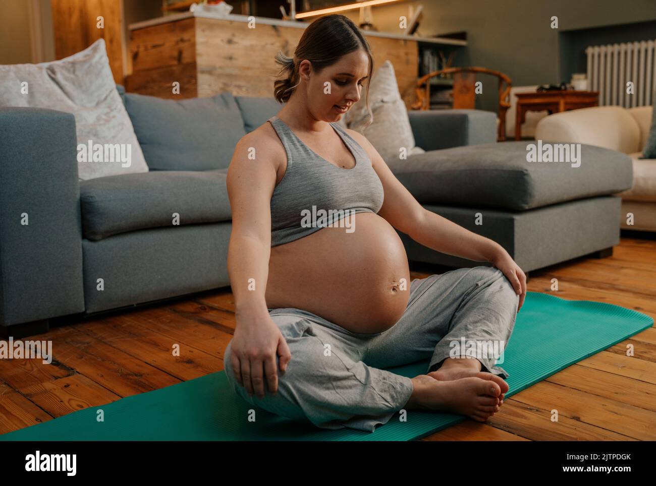 Donna incinta che fa yoga posa in soggiorno Foto Stock