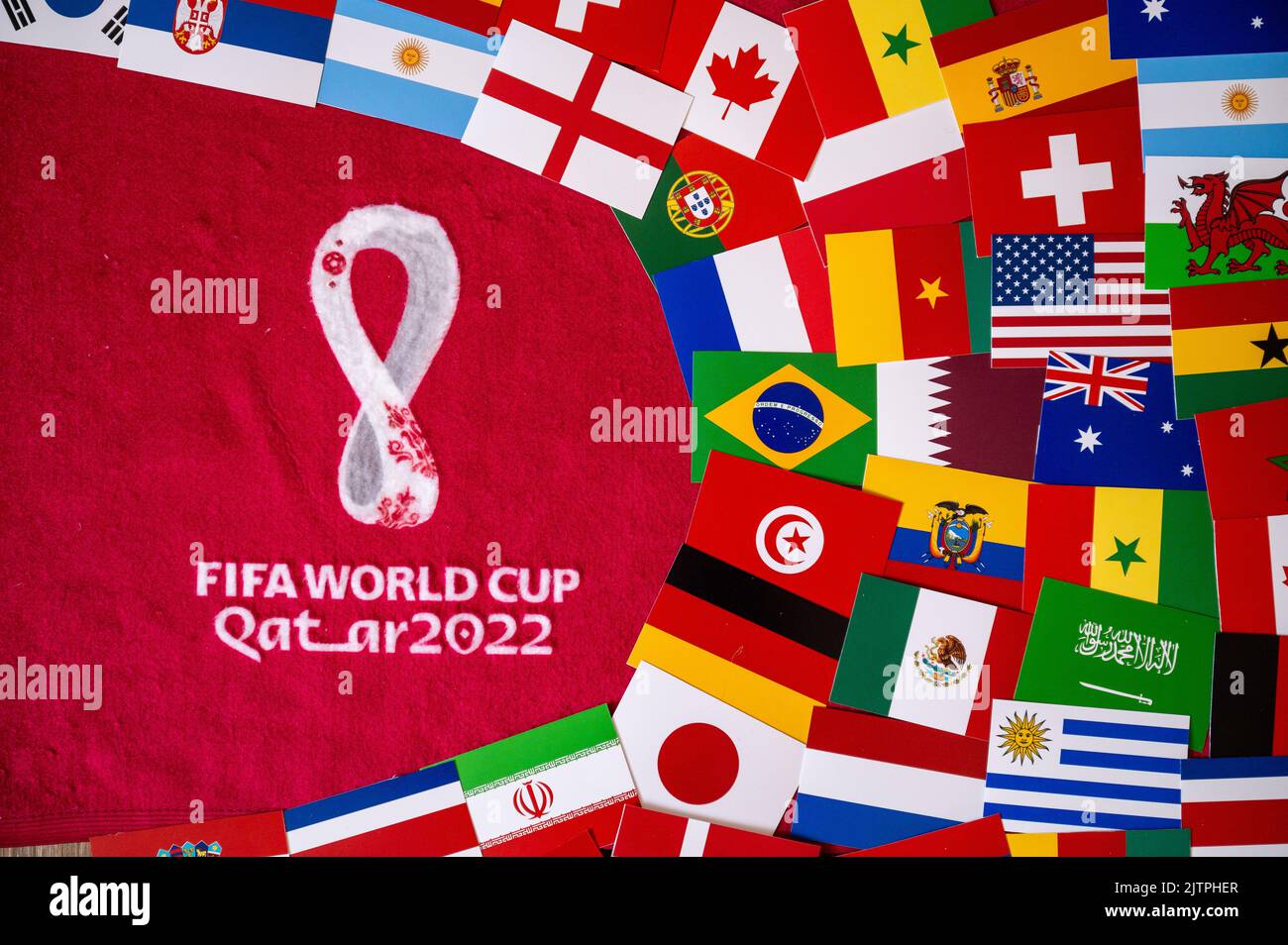 DOHA, QATAR, 30 AGOSTO 2022: Bandiere di tutte le 32 squadre che partecipano alla Coppa del mondo FIFA Qater 2022. Logo ufficiale del torneo di calcio su sfondo rosso Foto Stock