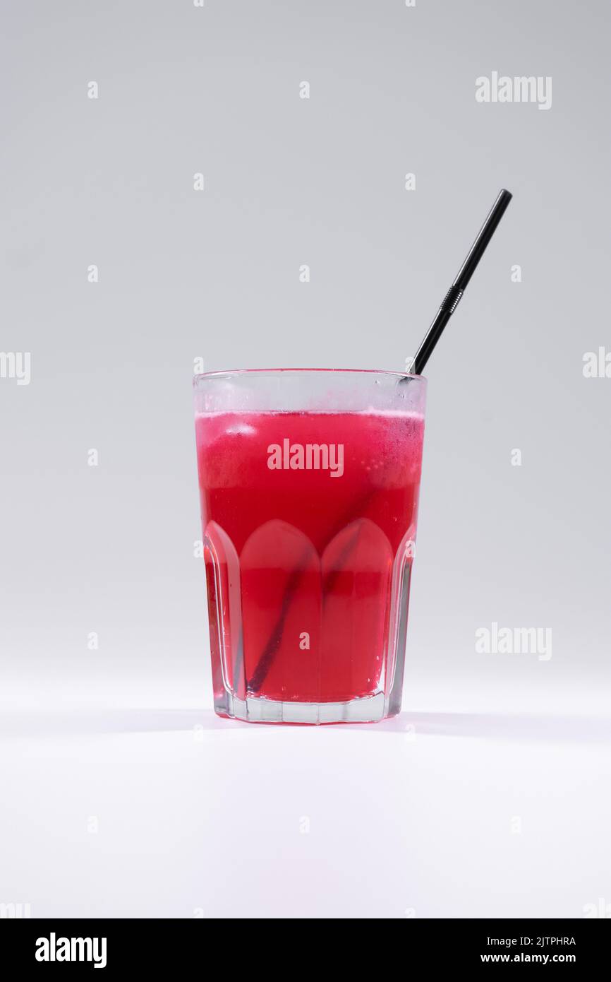 bevanda fresca di frutta fredda con succo d'uva rosso, ghiaccio, paglia isolata Foto Stock