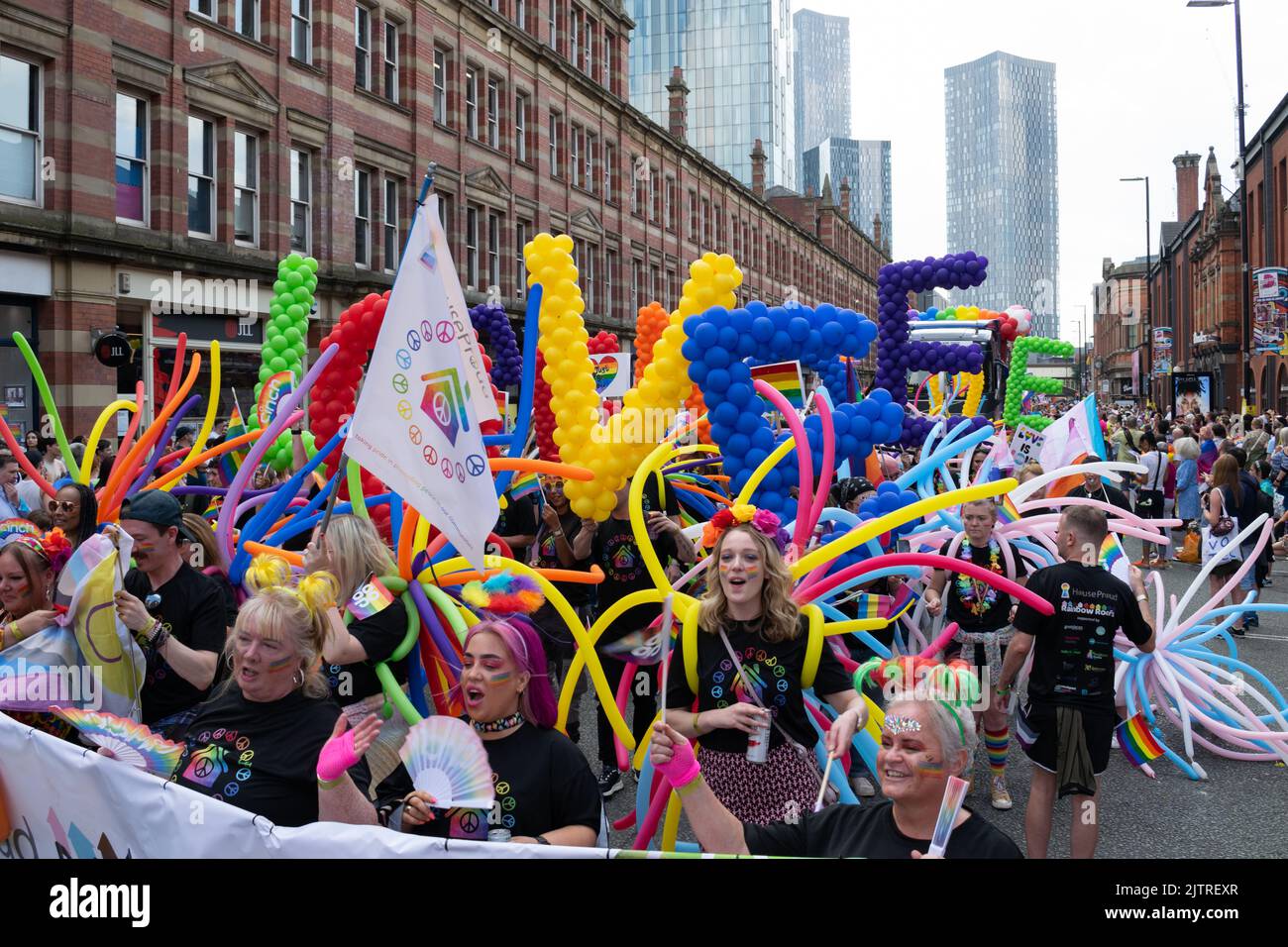 Sfilata del Manchester Pride. Casa orgogliosa lgbt sociale Housing Group. Marcia tematica per la Pace. Foto Stock