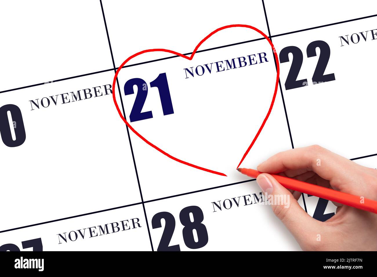 21st° giorno di novembre. La mano di una donna che disegna una forma a cuore rosso alla data di calendario del 21 novembre. Il cuore come simbolo dell'amore. Mese autunnale. Giorno del Foto Stock