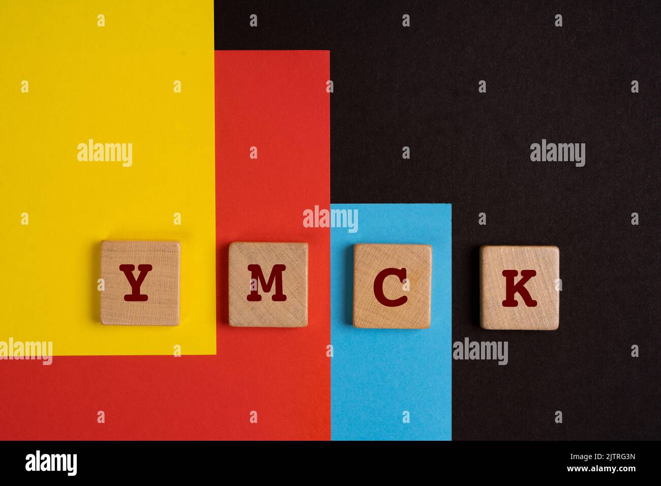 Spazio colore YMCK. Le lettere Y, M, C e K su un asciugamano di legno su sfondo giallo, rosso, ciano e nero Foto Stock
