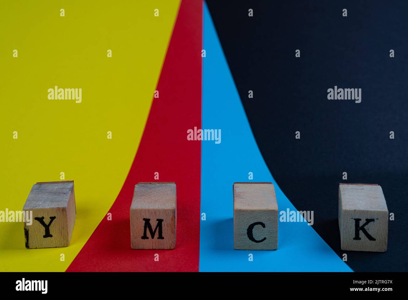 Spazio colore YMCK. Le lettere Y, M, C e K su un asciugamano di legno su sfondo giallo, rosso, ciano e nero Foto Stock