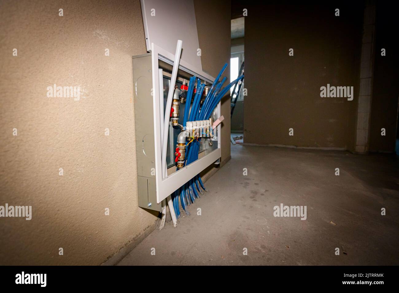 Le nuove valvole del collettore del sistema di distribuzione in ottone sono montate per il pavimento di riscaldamento centrale in un edificio residenziale in costruzione. Foto Stock