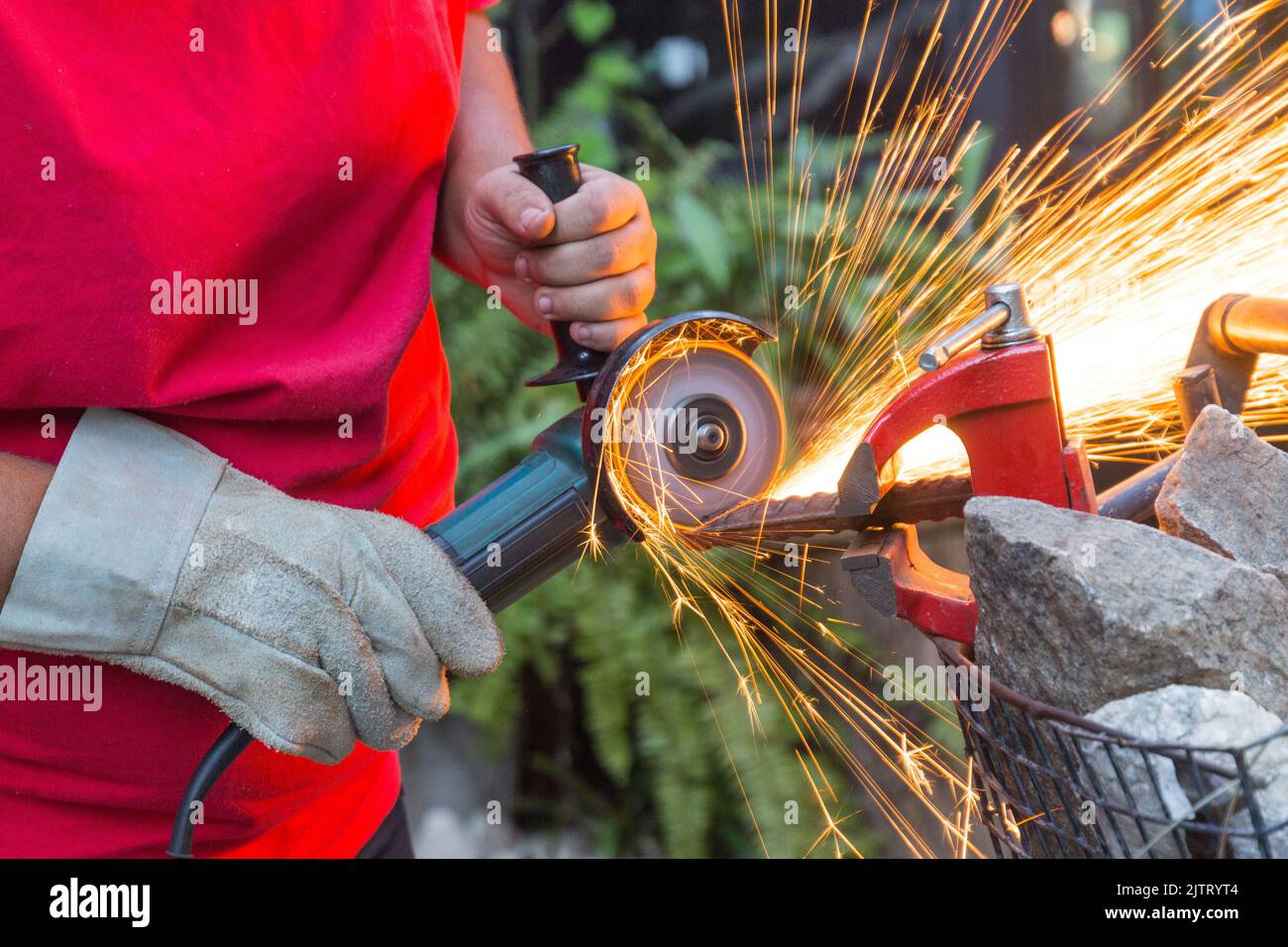 Fabbro uomo usando la sega per tagliare un pezzo di ferro. Foto Stock