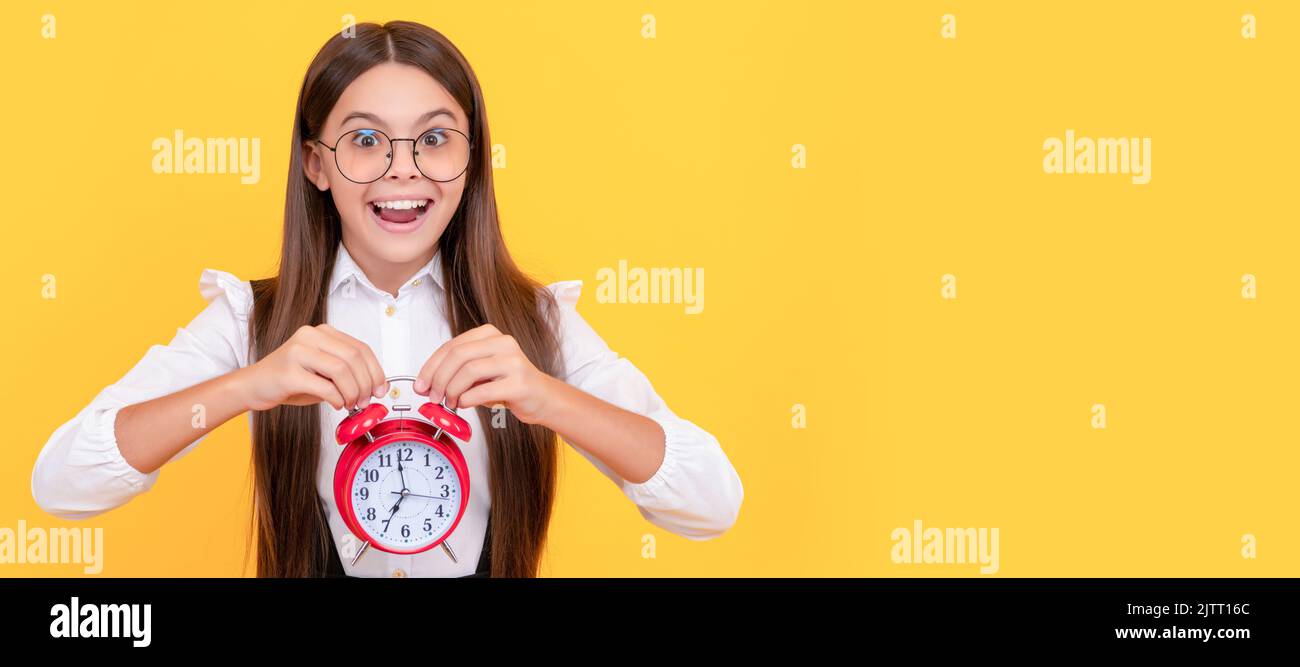 bambino della scuola in uniforme e occhiali che mostrano il tempo. sei in ritardo. scadenza. Buongiorno. Bambino adolescente con sveglia, poster orizzontale. Banner Foto Stock