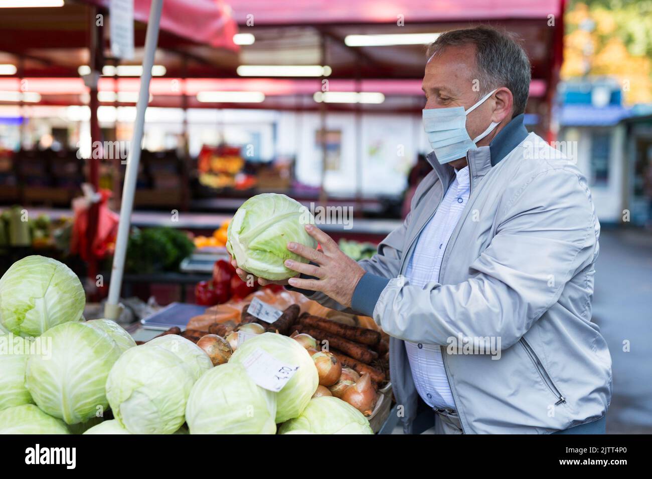 Uomo in faccia maschera scelta cavolo nel mercato Foto Stock