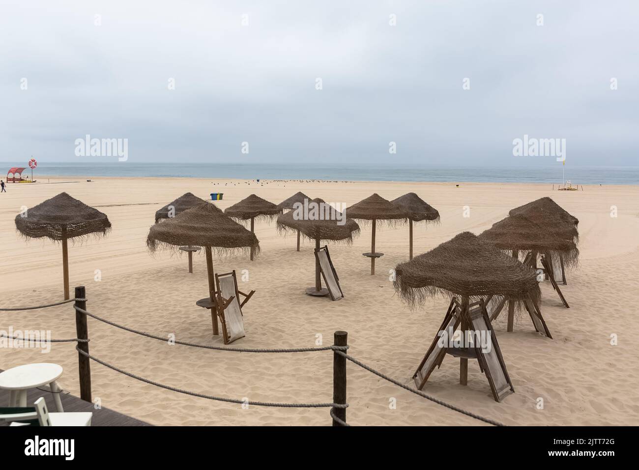 Panoramica generale vista sulla sabbia di Torreira spiaggia, spiaggia vuota, con i cappelli di paglia turistico, oceano atlantico sullo sfondo, Aveiro, Portogallo Foto Stock
