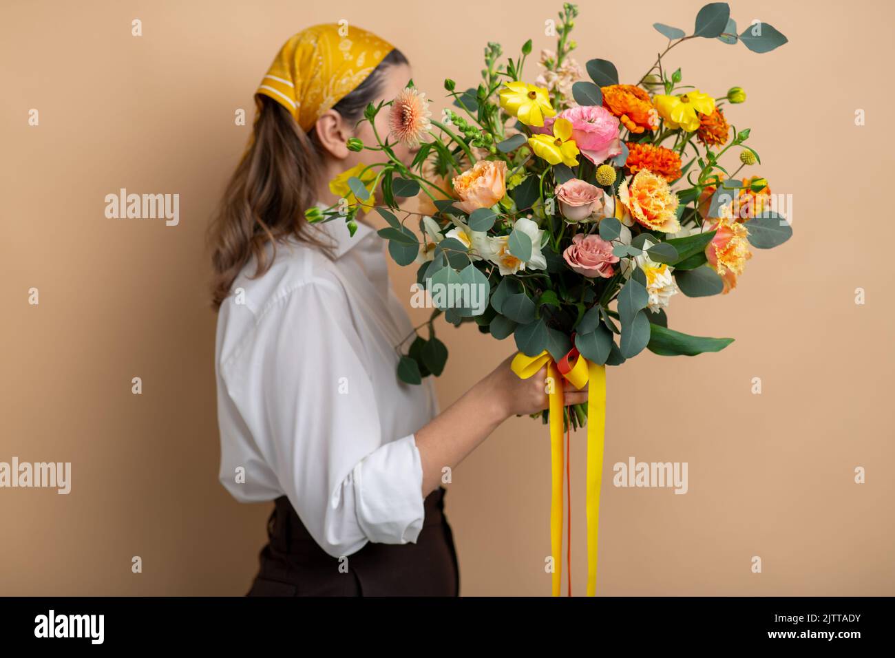 donna che tiene mazzo di fiori su sfondo beige Foto Stock