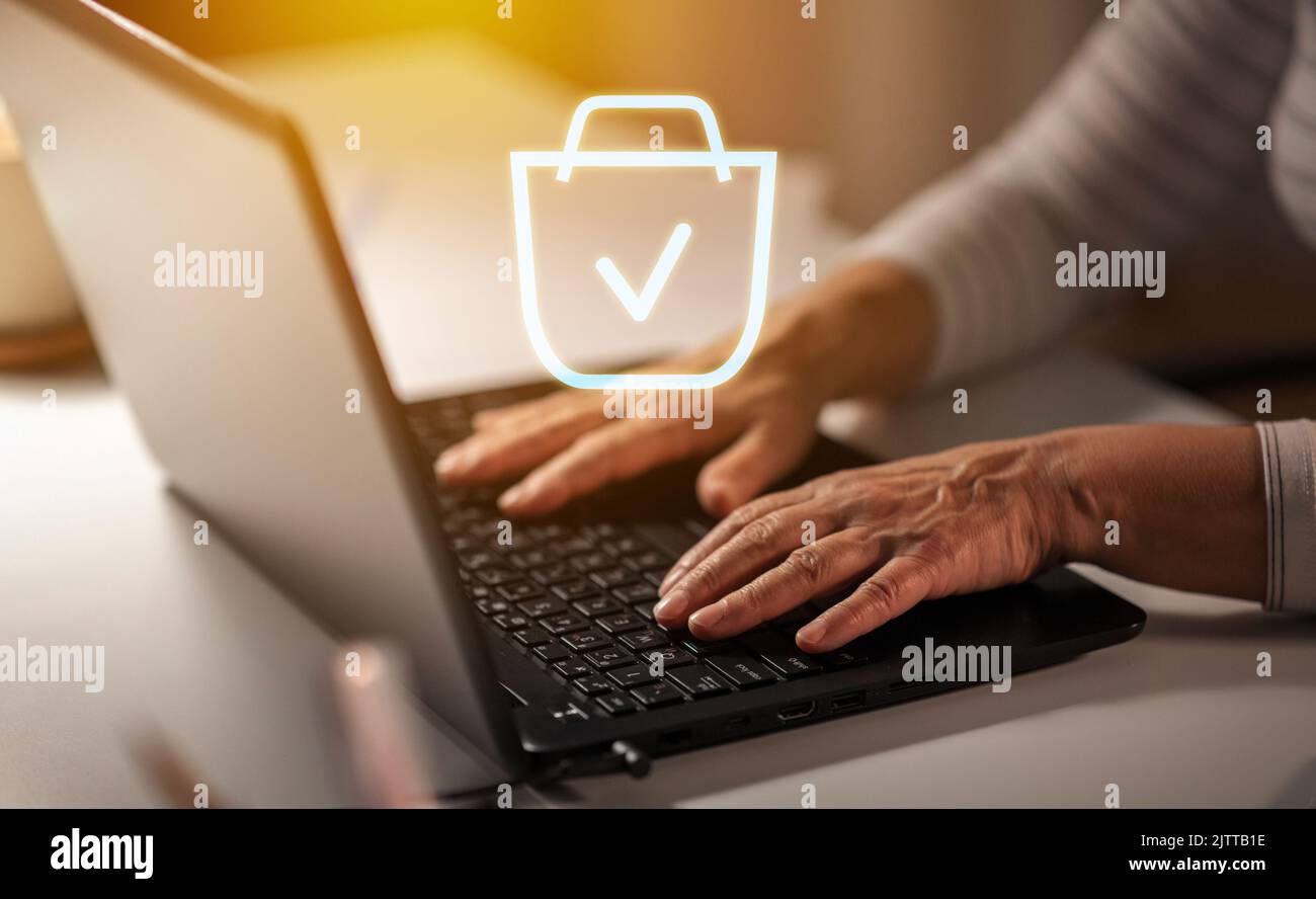 mani di una donna anziana con lo shopping online di notebook Foto Stock