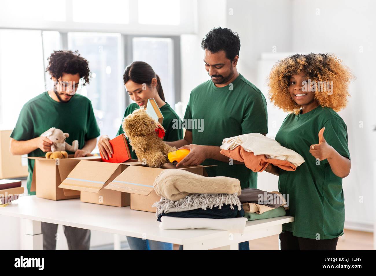 volontari imballando roba e mostrando pollici su Foto Stock