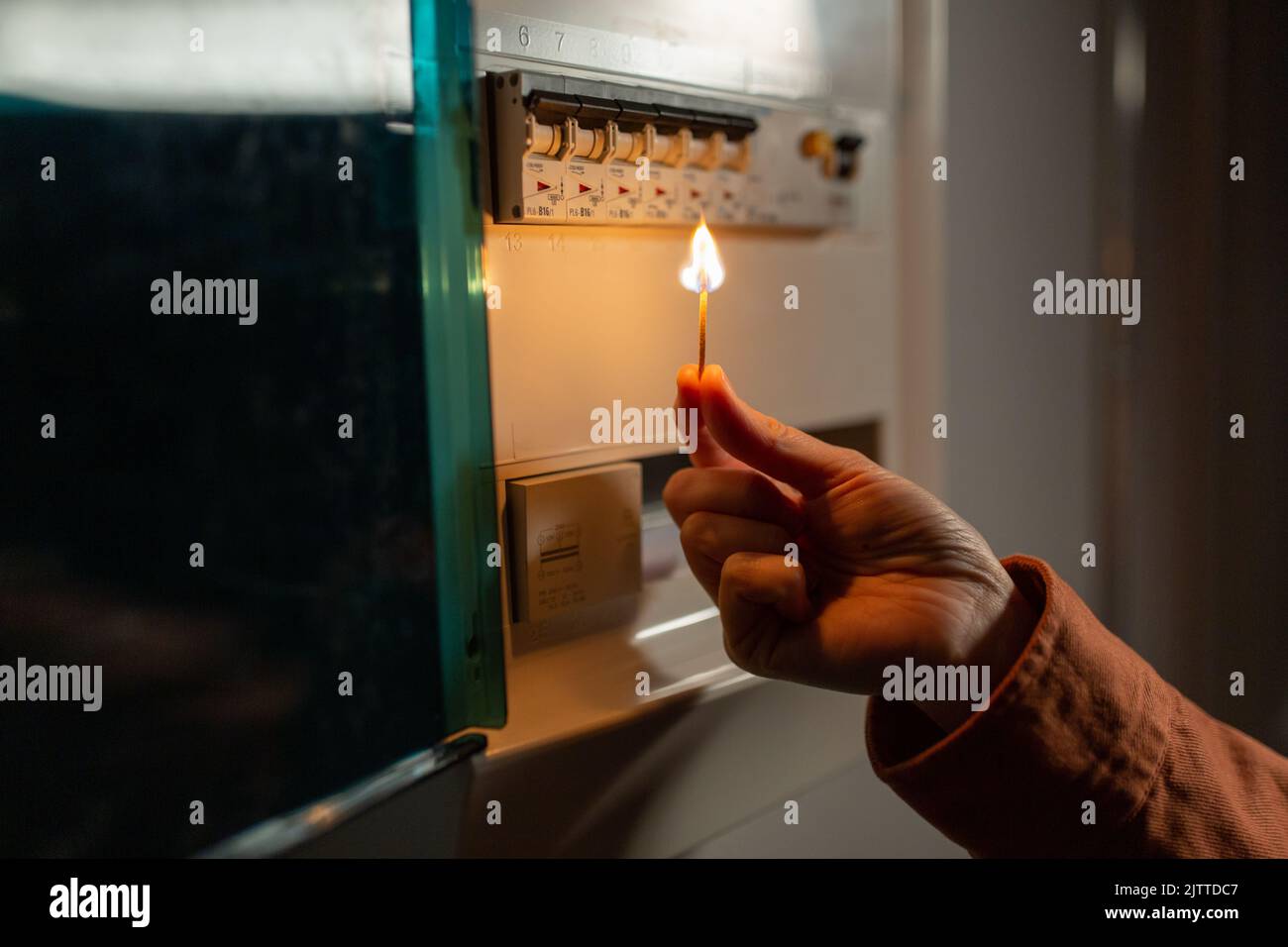 mano con fiammella bruciante vicino a tavola elettrica Foto Stock