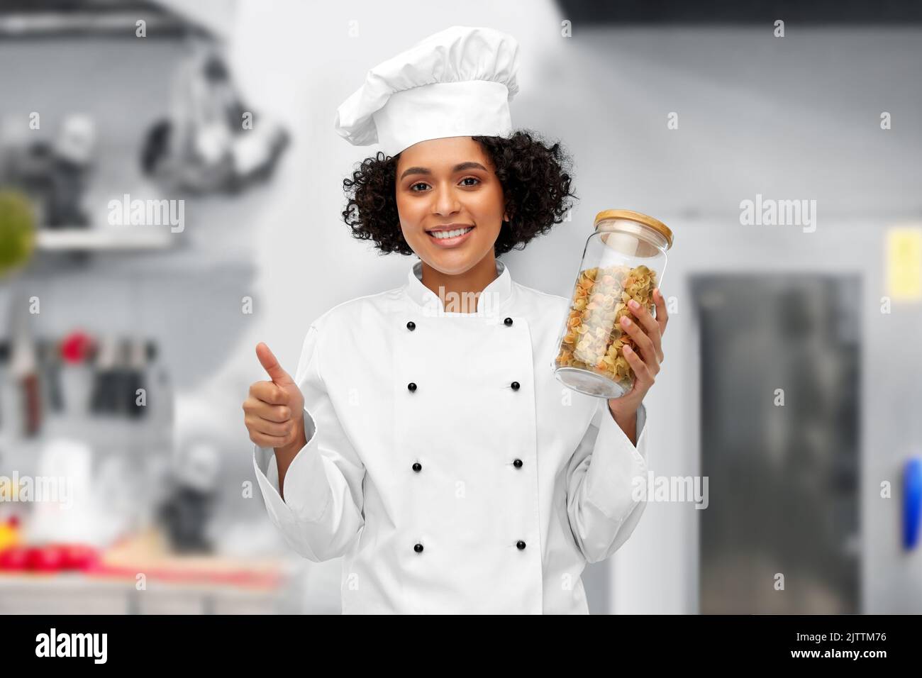 chef femminile con pasta in vaso che mostra i pollici in su Foto Stock